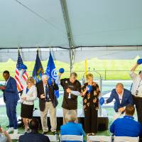 A group of people throwing down footballs on stage at the Jamie Hosford Football Center dedication.